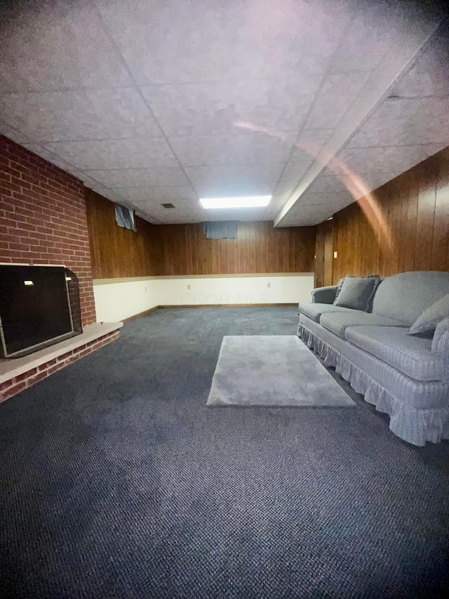 unfurnished living room with a brick fireplace, carpet floors, and wood walls