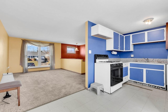 kitchen with pendant lighting, sink, blue cabinets, light carpet, and white gas stove