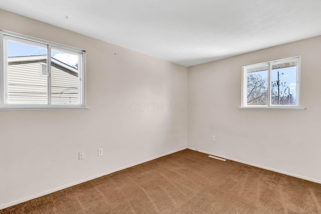 unfurnished room featuring plenty of natural light and carpet