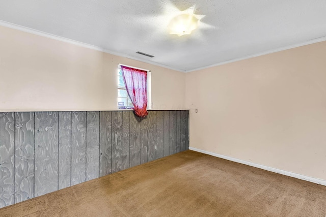 carpeted spare room featuring ornamental molding, wooden walls, and a textured ceiling