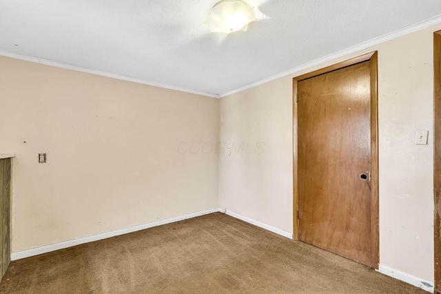 carpeted spare room featuring crown molding