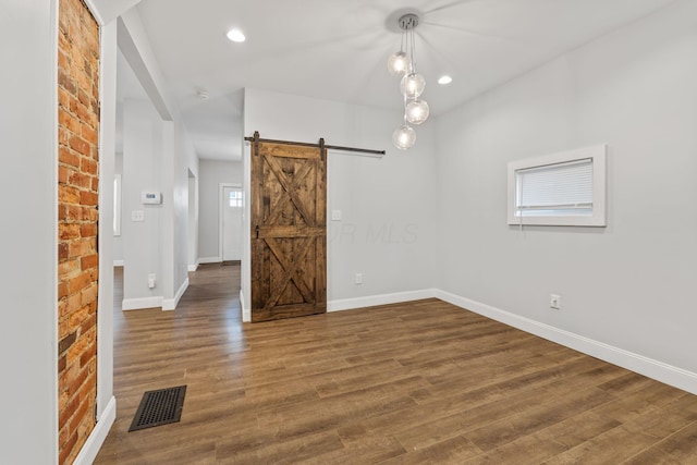 unfurnished room with a barn door and dark hardwood / wood-style flooring