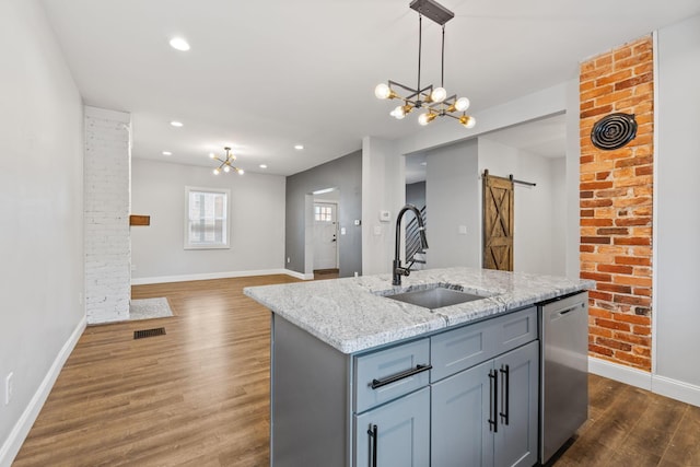 kitchen with sink, hanging light fixtures, a center island with sink, dishwasher, and a barn door