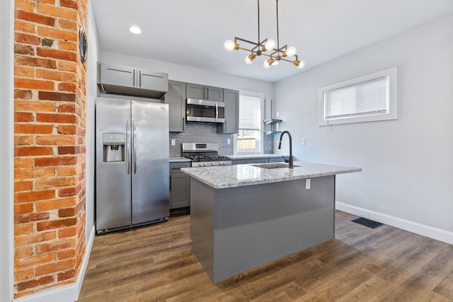 kitchen featuring light stone counters, appliances with stainless steel finishes, a kitchen island with sink, and sink