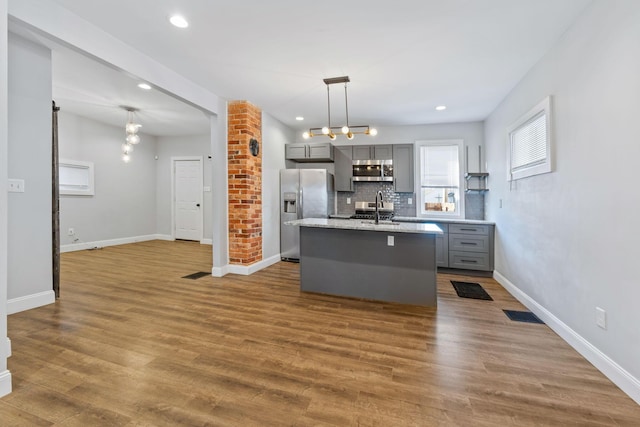 interior space with sink, gray cabinetry, appliances with stainless steel finishes, dark hardwood / wood-style floors, and pendant lighting