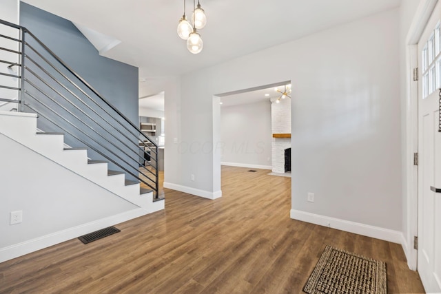 entryway with wood-type flooring and a brick fireplace