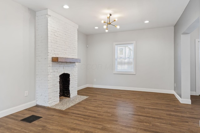 unfurnished living room with a fireplace, dark hardwood / wood-style flooring, and a notable chandelier