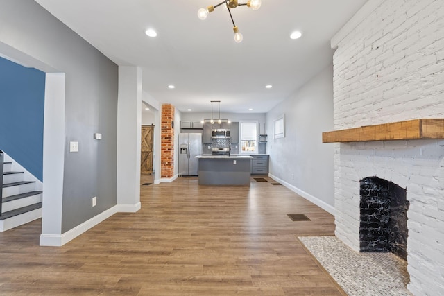 unfurnished living room featuring hardwood / wood-style flooring, a notable chandelier, and a fireplace