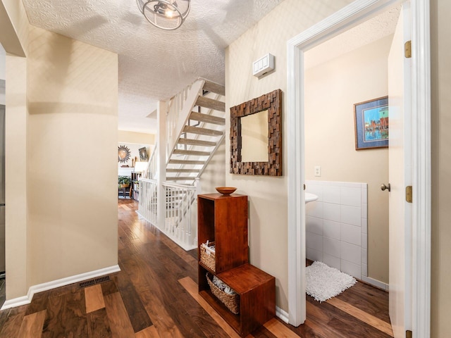 hall featuring wood-type flooring, tile walls, and a textured ceiling