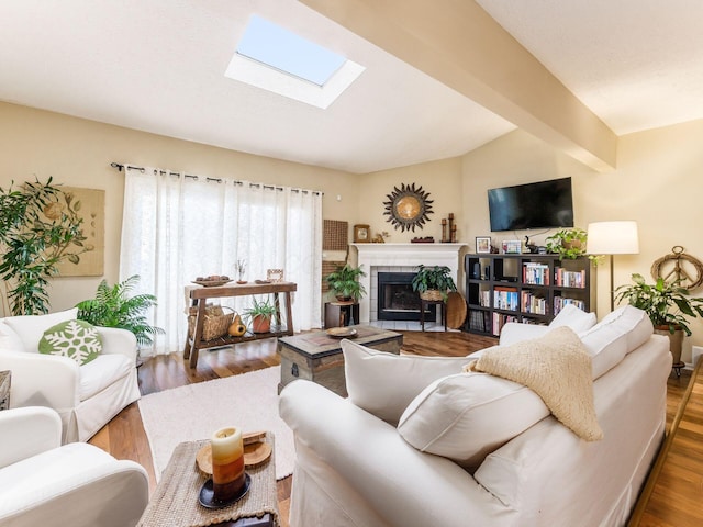 living room featuring dark hardwood / wood-style flooring, vaulted ceiling with skylight, and a tile fireplace