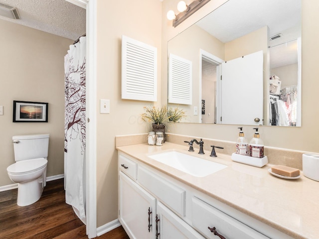 bathroom with vanity, toilet, hardwood / wood-style floors, and a textured ceiling