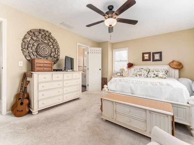 carpeted bedroom with ensuite bathroom, a textured ceiling, and ceiling fan