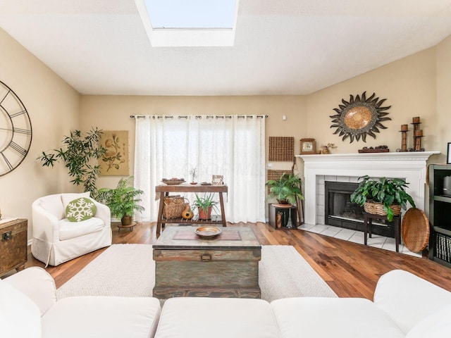 living room featuring a skylight, a tile fireplace, and light wood-type flooring