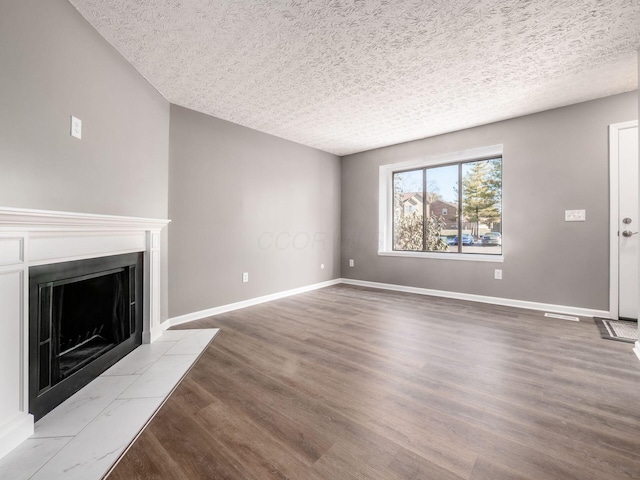 unfurnished living room featuring light hardwood / wood-style flooring and a textured ceiling