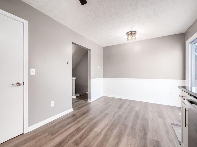 unfurnished dining area with a textured ceiling and light hardwood / wood-style flooring