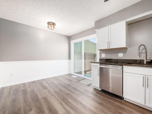 kitchen featuring white cabinetry, sink, stainless steel dishwasher, and a textured ceiling