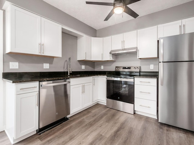 kitchen with a textured ceiling, light wood-type flooring, appliances with stainless steel finishes, ceiling fan, and white cabinets