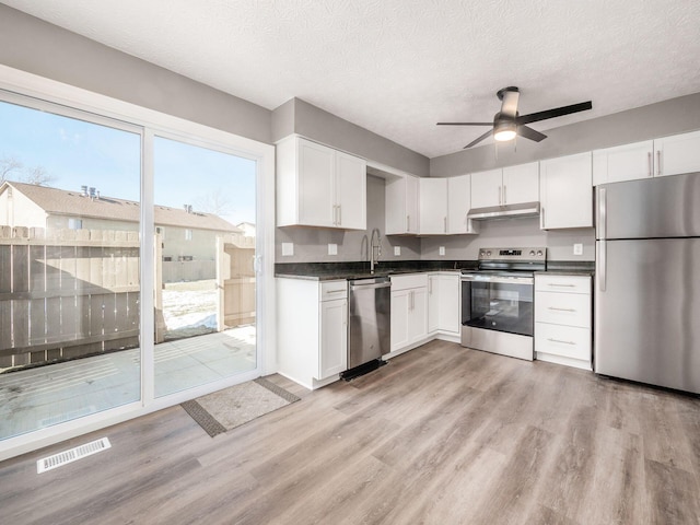 kitchen with appliances with stainless steel finishes, a textured ceiling, and white cabinets