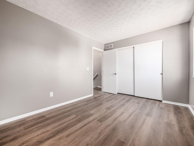 unfurnished bedroom featuring a closet, hardwood / wood-style floors, and a textured ceiling