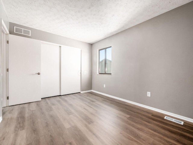 unfurnished bedroom featuring wood-type flooring, a textured ceiling, and a closet