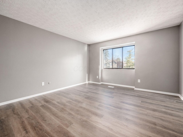 empty room with dark hardwood / wood-style flooring and a textured ceiling