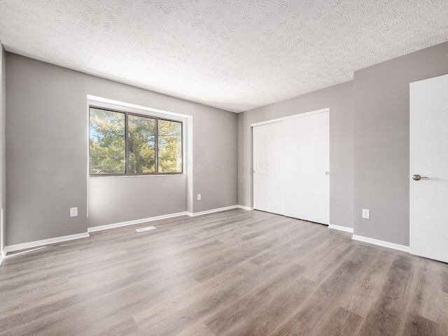 empty room with hardwood / wood-style flooring and a textured ceiling