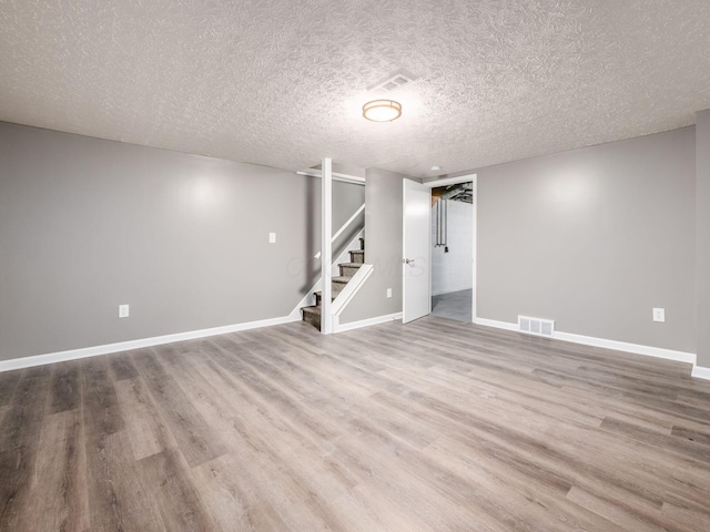 basement featuring hardwood / wood-style flooring and a textured ceiling