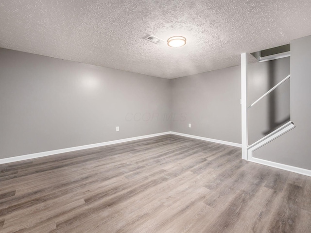 spare room featuring hardwood / wood-style flooring and a textured ceiling