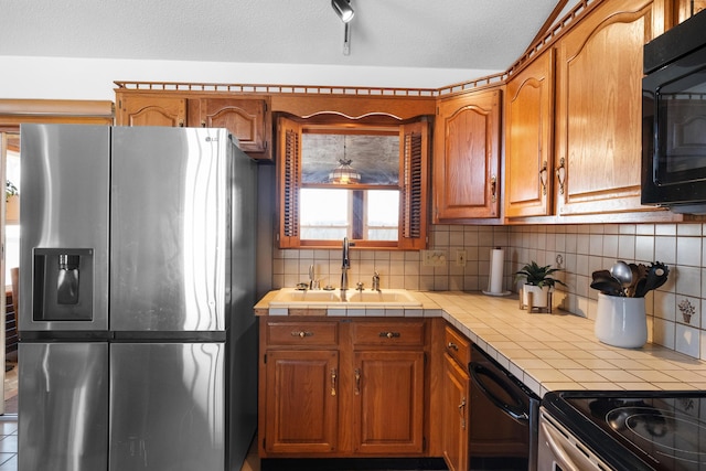 kitchen featuring sink, decorative backsplash, tile counters, black appliances, and a textured ceiling