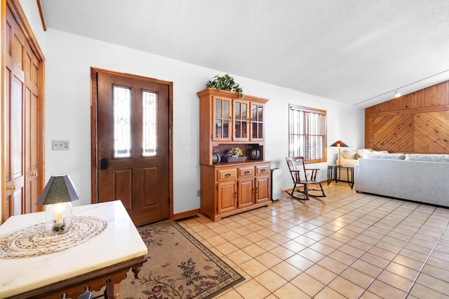 interior space with vaulted ceiling, a textured ceiling, and wood walls