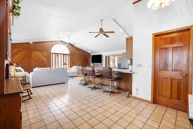 living room with ceiling fan, lofted ceiling, light tile patterned floors, and wooden walls