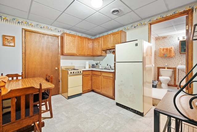 kitchen featuring sink, a drop ceiling, and white appliances