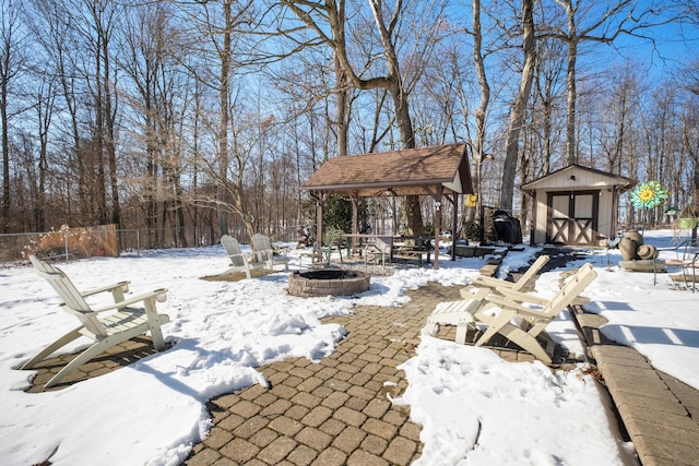 snow covered patio with a gazebo, a shed, and a fire pit