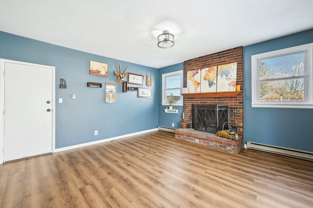 unfurnished living room with hardwood / wood-style flooring, a brick fireplace, and baseboard heating