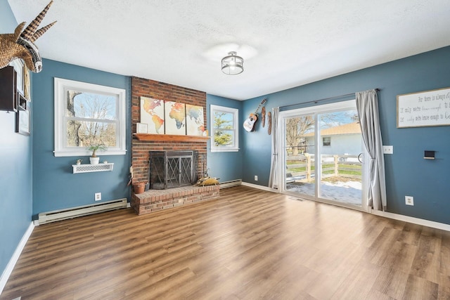 unfurnished living room featuring a baseboard radiator, hardwood / wood-style floors, a textured ceiling, and a fireplace