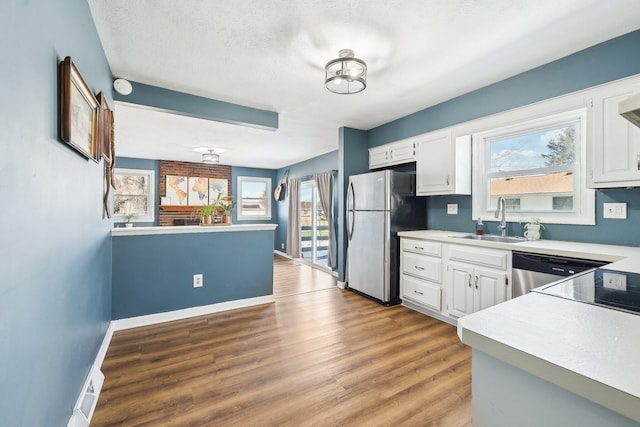 kitchen featuring sink, appliances with stainless steel finishes, white cabinetry, hardwood / wood-style floors, and a textured ceiling