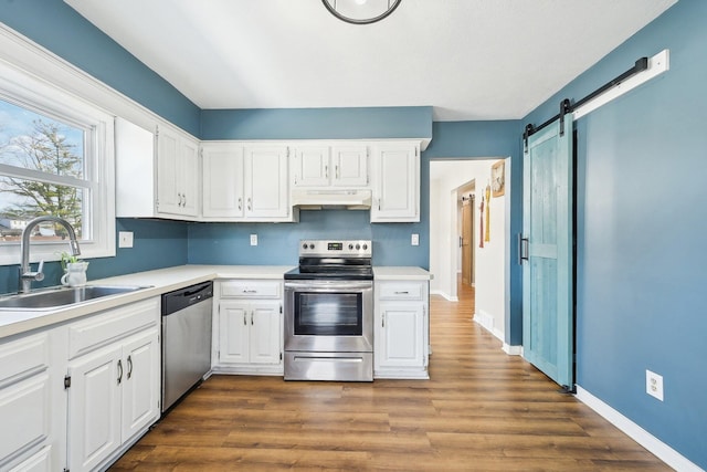 kitchen featuring a barn door, appliances with stainless steel finishes, sink, and white cabinets