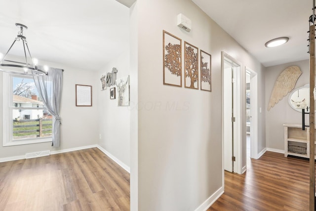 corridor featuring an inviting chandelier, hardwood / wood-style floors, and a barn door