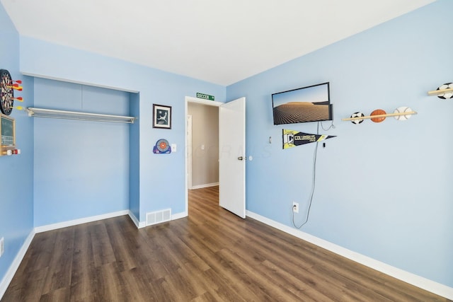 unfurnished bedroom with dark hardwood / wood-style flooring and a closet