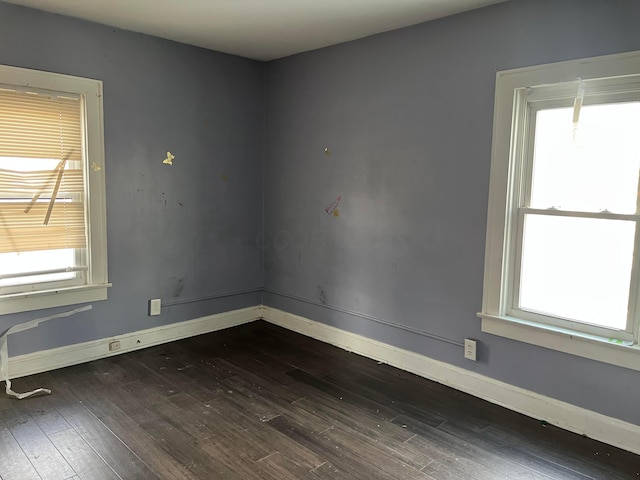 empty room featuring a wealth of natural light and dark hardwood / wood-style flooring