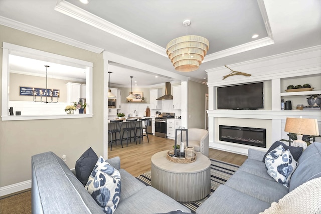 living room featuring an inviting chandelier, crown molding, a raised ceiling, and hardwood / wood-style floors