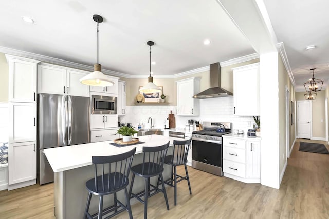 kitchen with wall chimney exhaust hood, a kitchen bar, tasteful backsplash, stainless steel appliances, and white cabinets