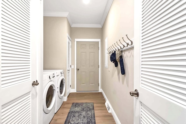 laundry room featuring crown molding, light wood-type flooring, and washing machine and dryer