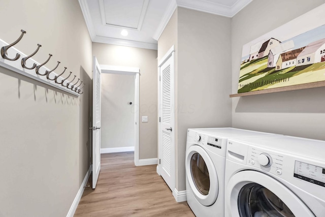 clothes washing area with crown molding, separate washer and dryer, and light wood-type flooring