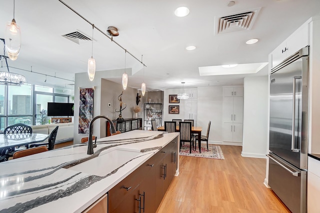 kitchen with white cabinetry, stainless steel built in fridge, and decorative light fixtures