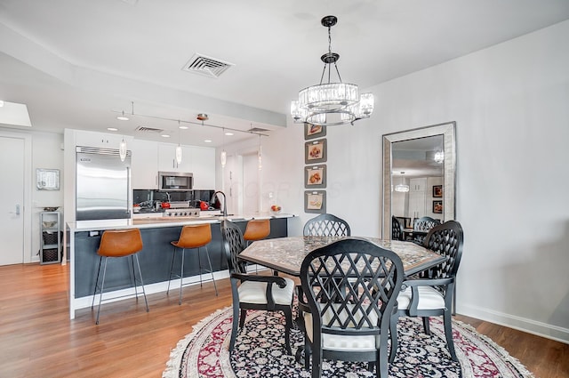 dining area featuring an inviting chandelier, sink, wine cooler, and light wood-type flooring