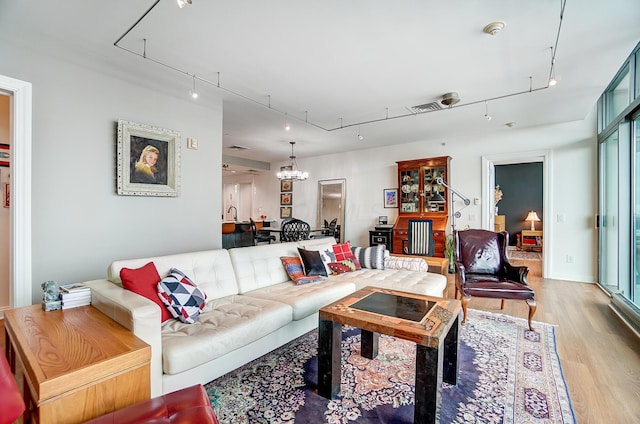 living room featuring track lighting, a chandelier, and light hardwood / wood-style flooring