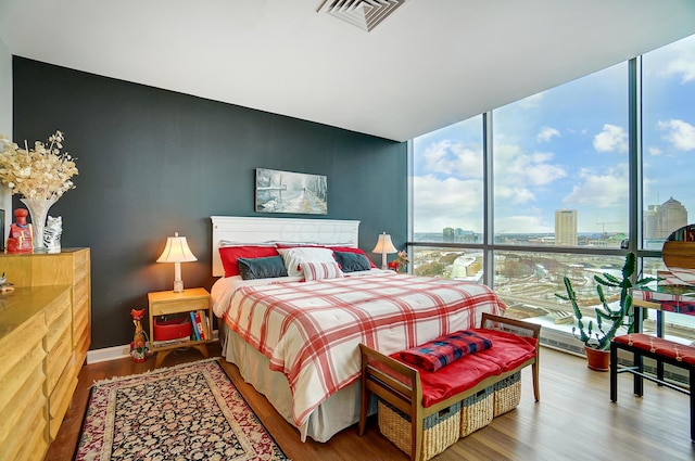 bedroom featuring expansive windows, wood-type flooring, and multiple windows