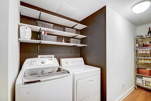 clothes washing area with light wood-type flooring and independent washer and dryer