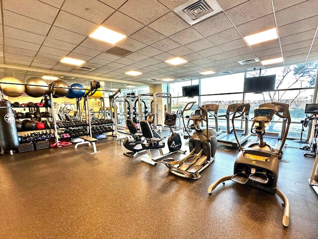 exercise room with a paneled ceiling and expansive windows